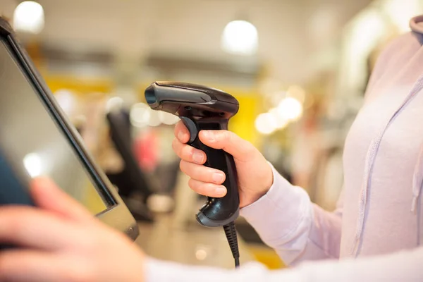 Jovem mulher mãos usando scanner para digitalizar bens para um pos para um cliente em enorme centro comercial, conceito de finanças — Fotografia de Stock