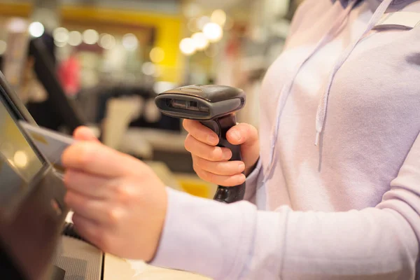 Jovem mulher mãos usando scanner para digitalizar bens para um pos para um cliente em enorme centro comercial, conceito de finanças — Fotografia de Stock