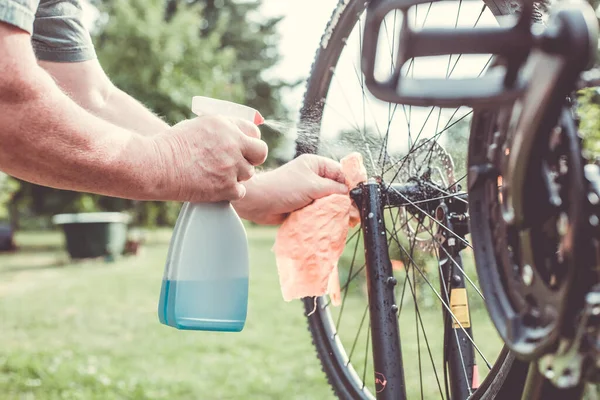 Senior man händer rengöring, rensa cykeln med spray och trasa, gör underhåll av sin cykel — Stockfoto