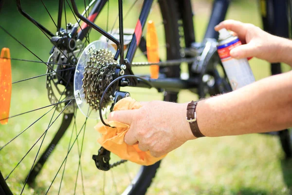 Senior man händer rengöring cykeln med spray och trasa, gör underhåll av sin cykel — Stockfoto