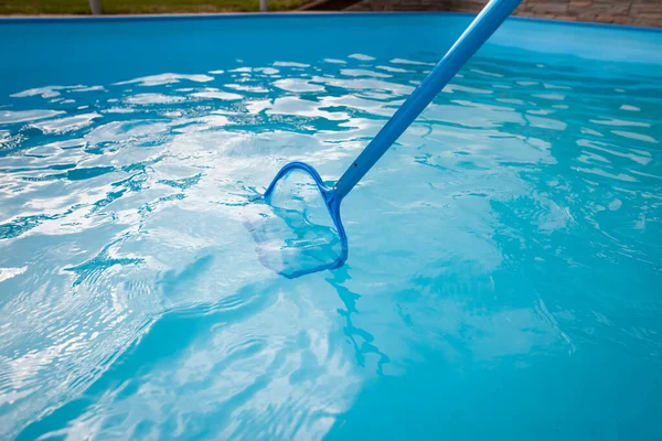 Young man hands cleaning pool by net of the dust, maintenance, clearing swimming pool