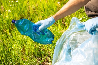 Plastik şişe toplayan bir adam, bir orman temizleme gezegeninde çöp toplama, çöp toplamaya yardım eden bir adam.