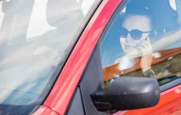 Mulher bonita usando um telefone inteligente, móvel durante a condução de um carro, conceito de transporte — Fotografia de Stock