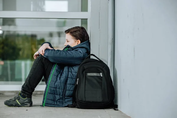 Menino ou criança sentado sozinho no chão em frente à escola depois de sofrer um ato de bullying — Fotografia de Stock