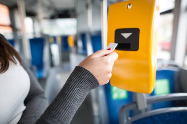 Genç kadın, otobüs biletini onaylayıcı, onaylayıcı ve tik tak, toplu taşıma konseptine sokuyor. 