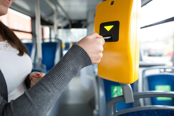 Joven mano inserta el billete de autobús en el validador, validación y tictac, concepto de transporte público — Foto de Stock
