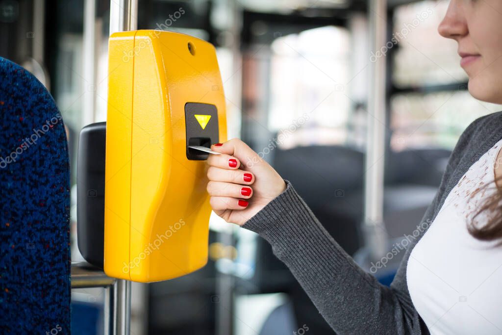 Young woman hand inserts the bus ticket into the validator, validating and ticking, public transportation concept 