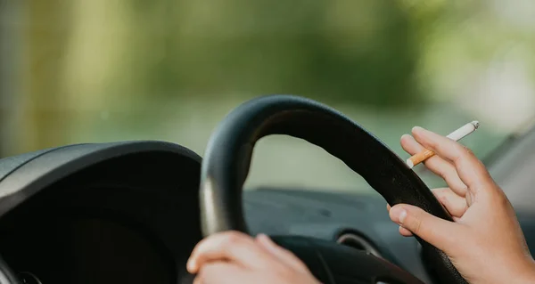 Mujer joven fumando un cigarrillo mientras conduce un coche, concepto de transporte — Foto de Stock