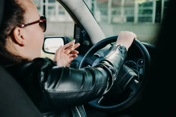 Mujer joven fumando un cigarrillo mientras conduce un coche, concepto de transporte — Foto de Stock