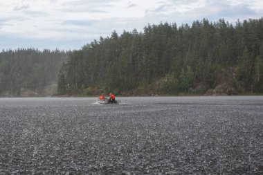 Fishermens bir botla göl sırasında şiddetli yağmur gidiyoruz