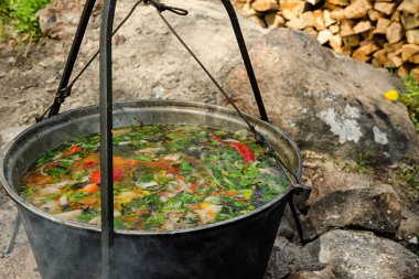 Bir tencere çorba ateşte kapandı. Arka planda yakacak odun vardır.