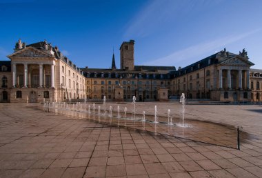 Sabahleyin Burgundy Dükleri Sarayı 'nda. Gökyüzü mavi. Dijon şehri. Fransa. Ön planda taş kiremitler ve bir çeşmeyle kaplı bir alan var..