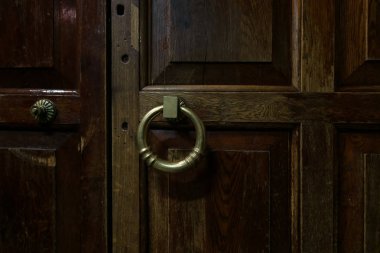 Koyu kahverengi, antika, ahşap bir kapının parçası. Sarı metalden bir halka şeklinde bir sapı var. Geçmişi. Doku.