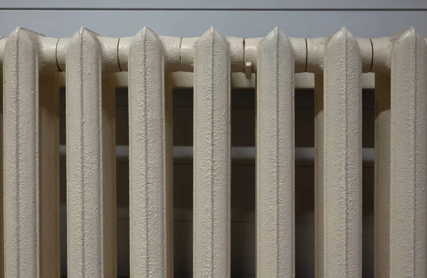 Eski bir dökme demir ısıtma kaloriferinin tepesinde. Açık bej rengin altında, döküm metalinin kırığı görülebilir. Geçmişi. Doku.