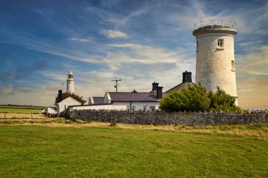 Yeşil çayırlar arasında tarihi bir deniz feneri bulunan Galler kıyıları.