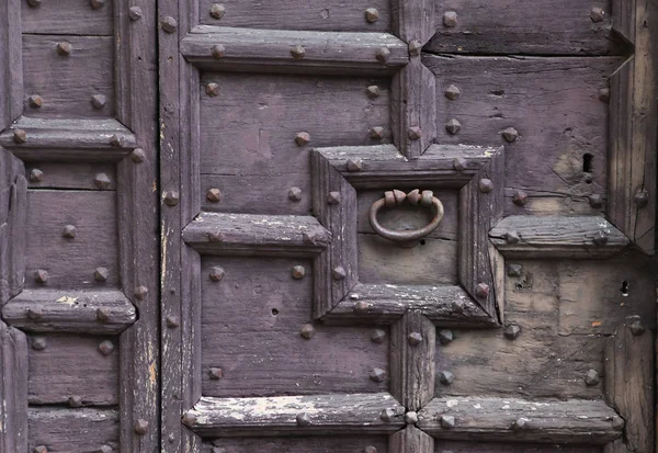 Background: fragment of a wooden door - boards painted in a dark blue cap and forged iron nails and door handle. Style Medieval Europe (France).