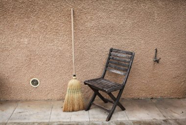 Vintage şeyler: eski Fransız Bahçe ahşap sandalye ve odun şömine veya soba ve süpürge için katlanır tabure ve hasır sepet. arka plan - sarı pembe duvarlar. Provence. Fransa.