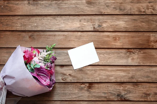 Blommor ligga på en trä bakgrund, bord, golv och kuvert med Tom gåva tagg Stockbild