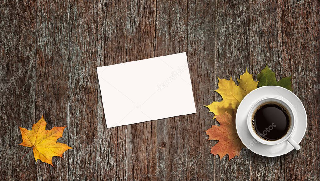 White list on wooden background. Yellow leaves and a cup of tea