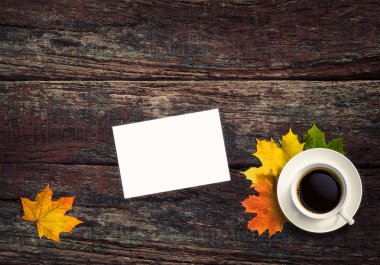 Ahşap arka plan üzerinde beyaz liste. Sarı yapraklar ve bir fincan çay