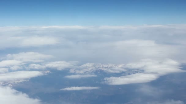 View from the clouds to the snow-capped mountains. Shooting from very high altitude. Beautiful blue sky. — Stock Video