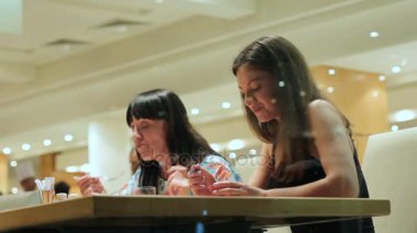 Anne ve kızı restoran ve şirin konuşma yiyin. İki güzel esmer üzerinde büyük bir pencereden görüntüleme.
