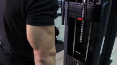 Atlet kasları yukarı kaldırarak büyük ağırlık tarafından üzerinde simülatörü pompalar. Erkek triceps yakın çekim.