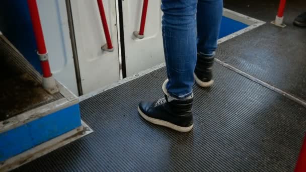 Vieja trolebús desde el interior en mal tiempo. Los pies humanos calzados en zapatillas negras salen del transporte público . — Vídeos de Stock