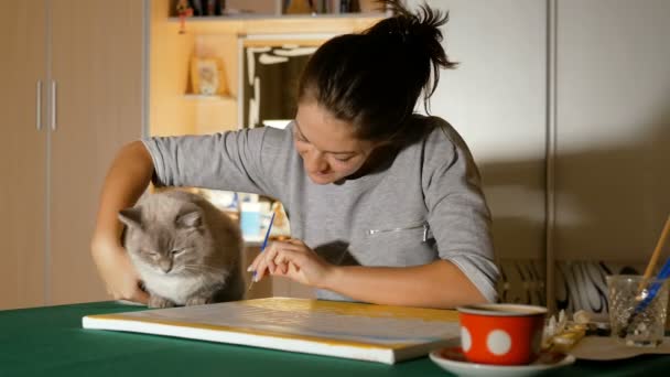 Mooi meisje spelen met haar huisdier. Een jonge kunstenaar probeert te leren van een kat te tekenen. Eigenaren en hun grappige dieren. — Stockvideo