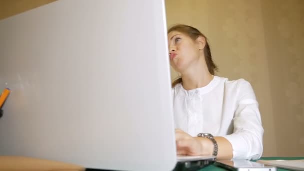 Uma garota vestida com uma blusa branca digitando no laptop como louca. Consequências do longo trabalho . — Vídeo de Stock