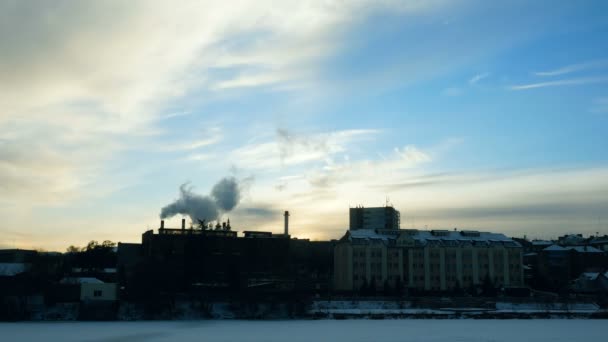 Timelapse video s výhledem na zimní město na řece. Z komína rostliny vychází hustý kouř. Znečištění životního prostředí. — Stock video
