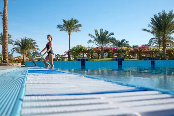 Genç kadın güzel bir iş parça mayo spor havuzda çıkar. Modern insan Resort aktif dinlenme.