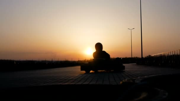 Carrera en karting al atardecer. Circuito de carreras por la noche. Los tíos con cascos compiten por la velocidad. Los coches están avanzando a alta velocidad . — Vídeos de Stock