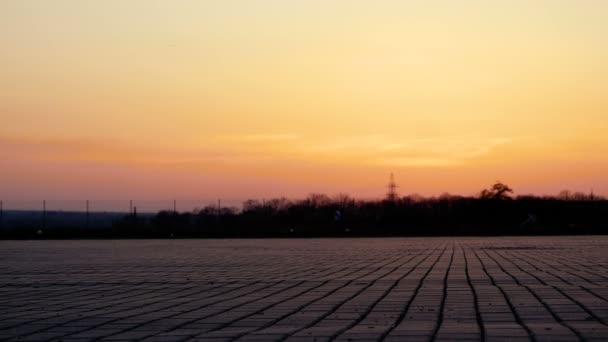 Silhouette of a young woman who rides on an ATV over a large square in the background of a beautiful sunset. — Stock Video