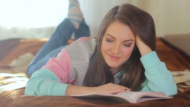 Νεαρή όμορφη γυναίκα διαβάζοντας ένα βιβλίο προσεκτικά και να διασκεδάζουν. Χαριτωμένο χαμόγελο ένα ωραίο μοντέλο. Μελαχρινή με μπλε μάτια — Αρχείο Βίντεο