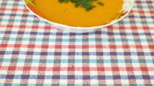 Camera moves forward on the pumpkin cream soup cooked and decorated with greens in a plate. Healthy food — Stock Video