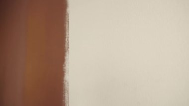 Boya silindiri. Beyaz, çıplak bir duvarı yukarı aşağı fırçalamak. Kahverengi renk. Tasarım konsepti. Bir ofis odasının onarım ve onarım işleri. Bir sapı yakın çekim.