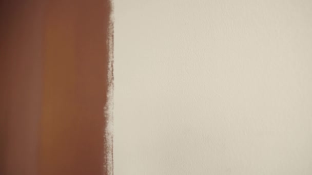 Rodillo de pintura. Cepillando una pared desnuda blanca arriba y abajo. Color marrón. Concepto de diseño. Trabajos de reparación y mantenimiento de una sala de oficina. Primer plano de un mango . — Vídeos de Stock