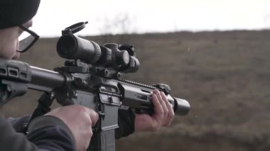 Sivil giysiler içinde bilinmeyen bir lehimin açık havada dürbünlü bir saldırı tüfeğinden çekilmiş görüntüleri. Kar yağıyordu. Çıplak eller. Askeri harekatlar. Siyah alan.