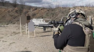 Gaz maskeli, kasklı ve can yelekli bilinmeyen bir asker dürbünlü bir tüfekle ateş ediyor. Acemi bir çaylak dışarıda antrenman yapıyor. Bir amir onu izliyor..