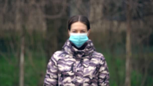 Jonge vrouw doet een medisch masker af en kijkt naar de camera. Gezondheidszorg en medisch concept. De pandemie is voorbij.. — Stockvideo