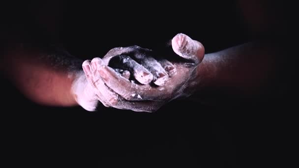 Movimiento lento de las manos con salpicaduras de polvo aplaudiendo las manos. mano salpicadura con harina sobre fondo negro . — Vídeo de stock