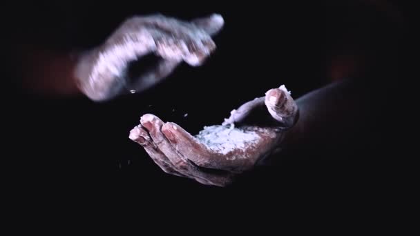 Powolny ruch dłoni z rozbryzgiem proszku poprzez klaskanie w dłonie. rozprysk dłoni z mąką na czarnym tle. — Wideo stockowe