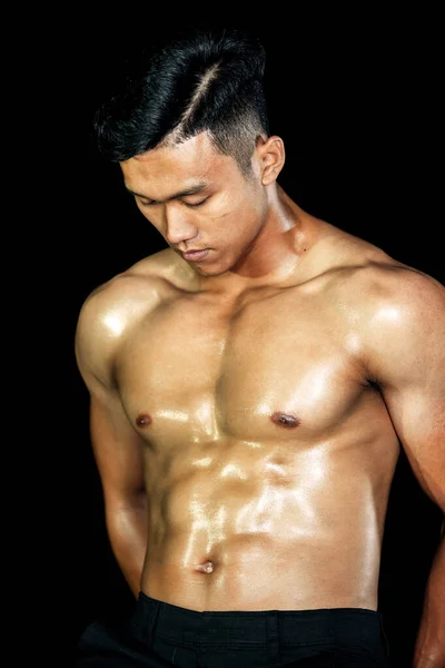 Asiatischer Bodybuilder stattliche Männer posieren vor schwarzem Hintergrund mit Muskeln. Fitness Körpergymnastik große Brust und Schulter und Bizeps. Gesunder idealer Körpertyp. Stockbild