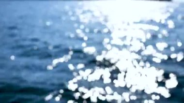 Okyanus dalgalarının yüzeyindeki güneş ışığının Bokeh yansıması. Güzel bir serenat arka planı. Teknede sallanan video