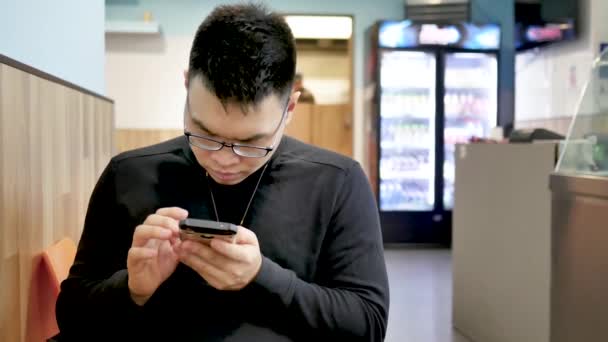 亚洲男人在公共餐馆专心致志于智能手机 在手机上输入讯息 — 图库视频影像