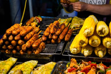 Vietnam 'daki Phu Quoc adasında sokak yemekleri. Geceleri markette turistler için sarı ışık altında nefis bir bbq sosisi sergisi.