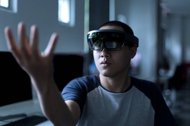 Laboratuvarda VR gözlükleriyle gerçeği karıştırmaya çalışan Asyalı genç bir öğrenci. Sanal gerçeklik kulaklığı kullanırken erkeklerin hareketi.