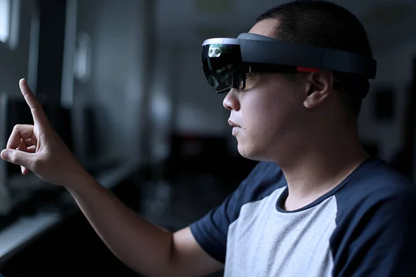 Young asian student trying Mixed reality with VR glasses in the laboratory. Gesture of men when using Virtual Reality headset.