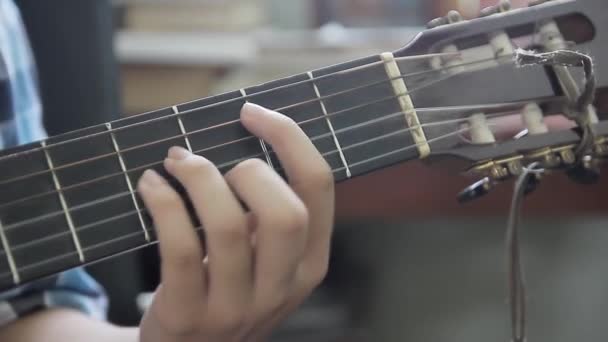 Jovem aprende a tocar guitarra, vê de perto a sua mão. Guitarrista editar cordas de guitarra . — Vídeo de Stock